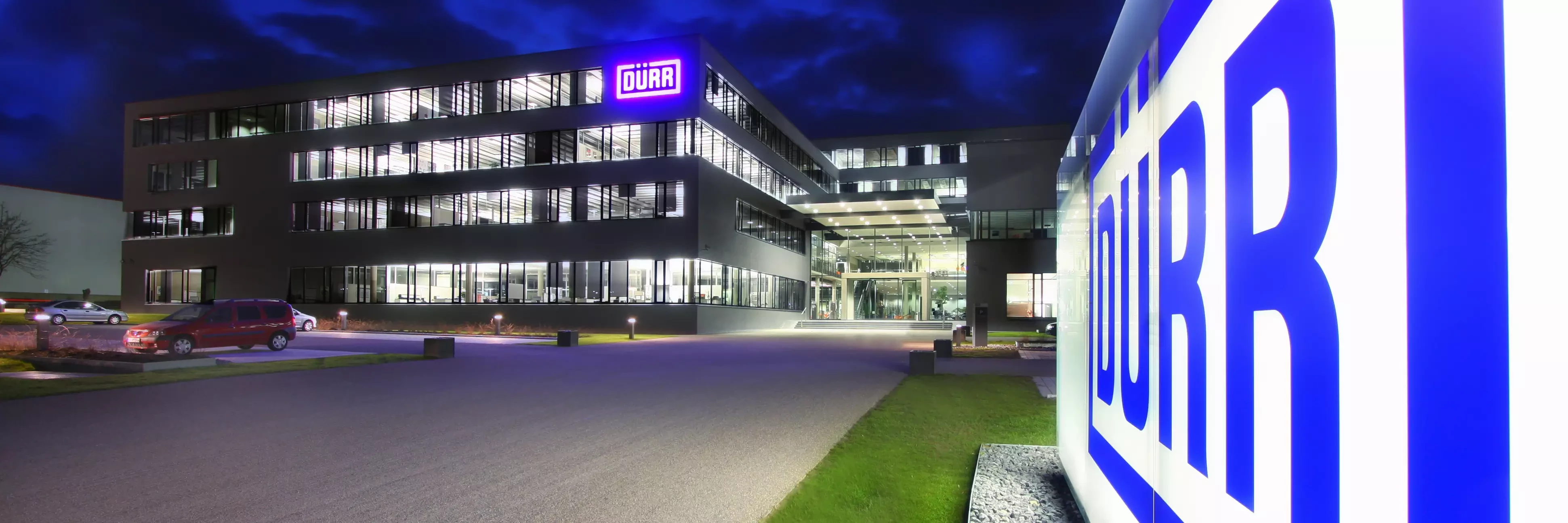 Dürr location headquarters in germany at night viewing the shining logo in the front of the building.